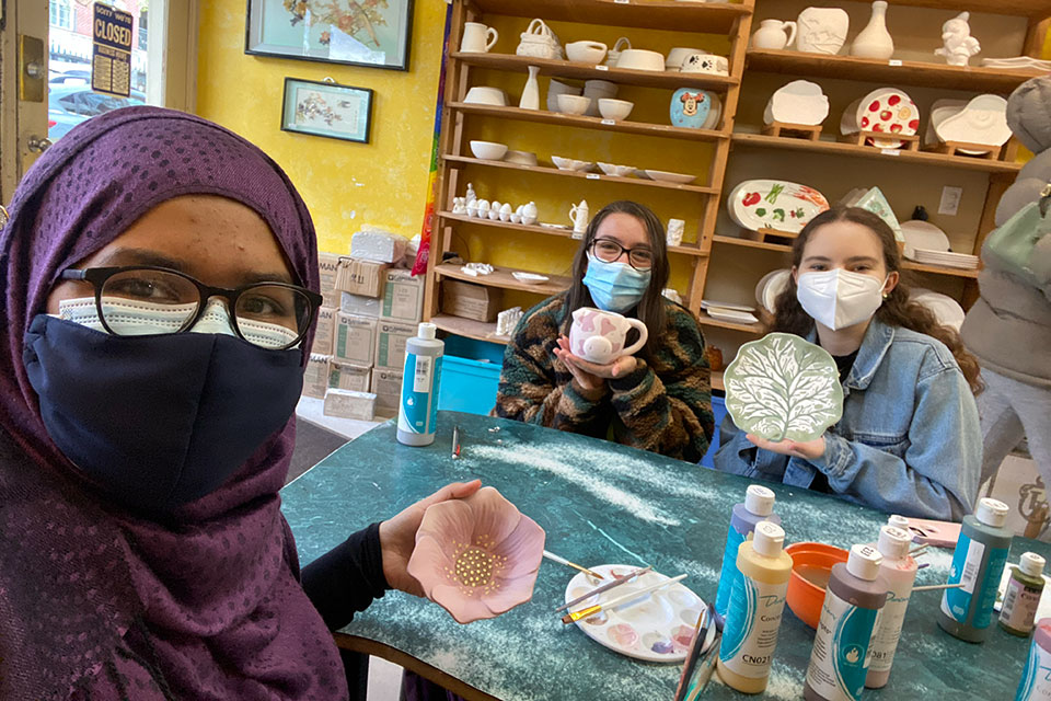 Jasia with friends displaying their pottery creations