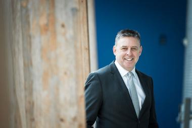 Dr. John Oliffe in front of blue background