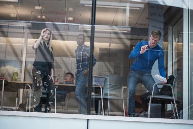 Students writing on a glass wall doing collaborative work