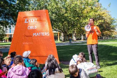 Danilo Caron speaks to children next to the engineering cairn
