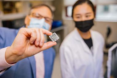 Two lab personnel looking at a machine part