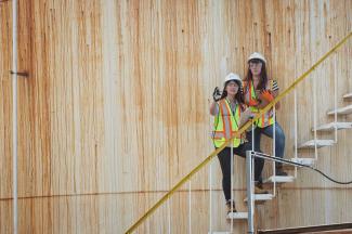 Two students standing in an outdoor stairwell observing the project site.
