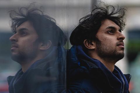Man leaning against a reflective wall, looking up