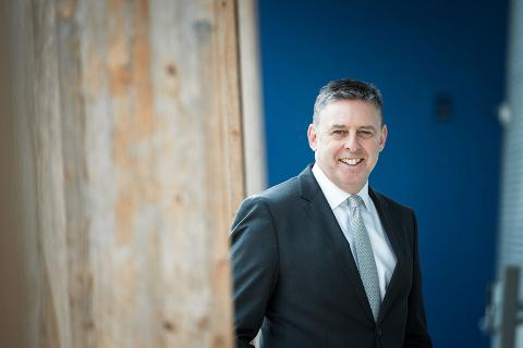 Dr. John Oliffe in front of blue background