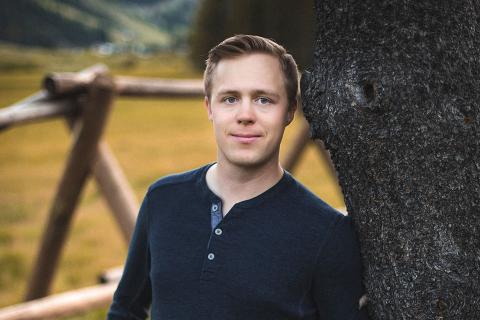 UBC Mining Engineering graduate Tenaya Brown smiles for the camera, centered in the frame next to a tree with a fence and green pasture in the background
